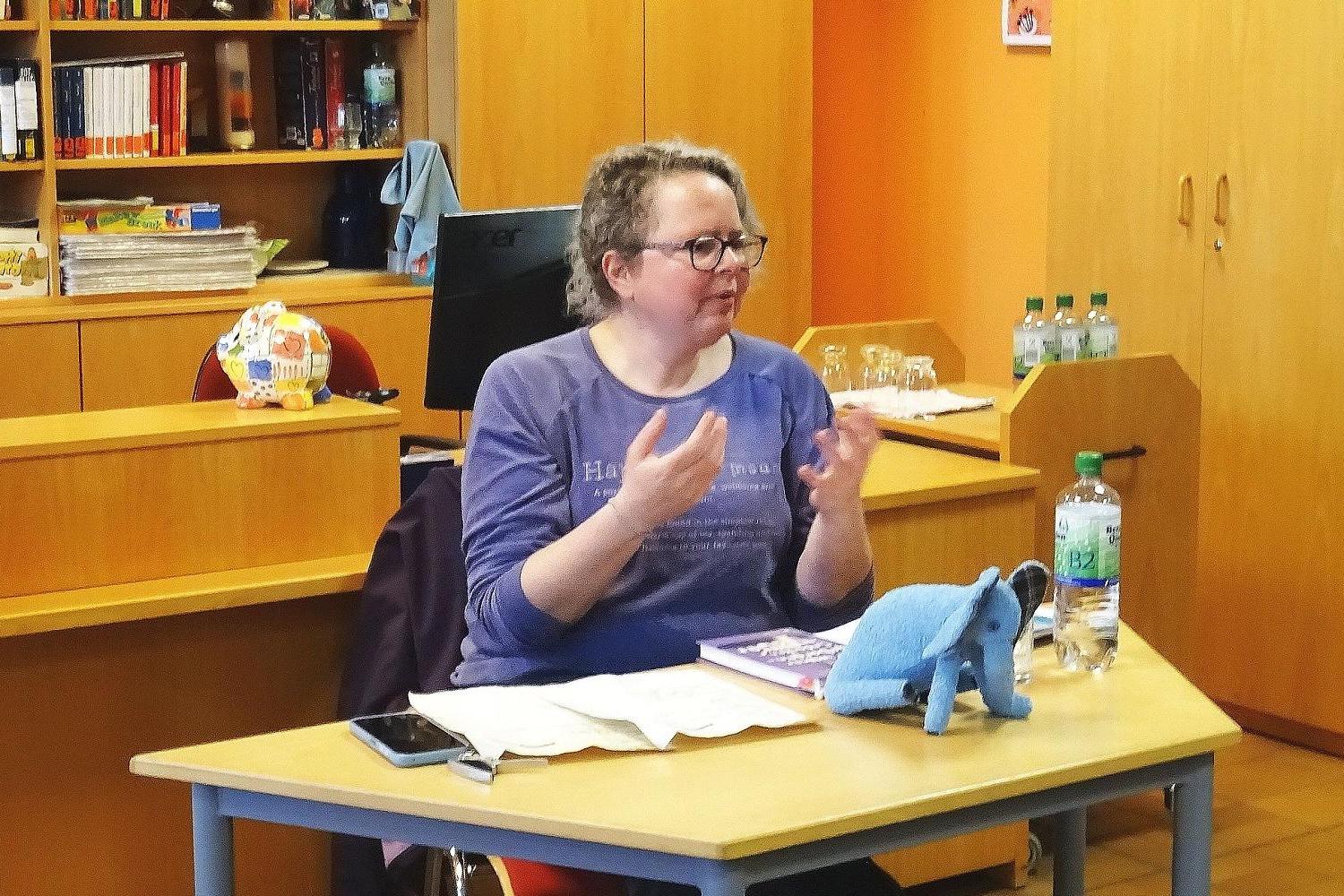 Eine Dame sitzt an einem Tisch und erzählt
