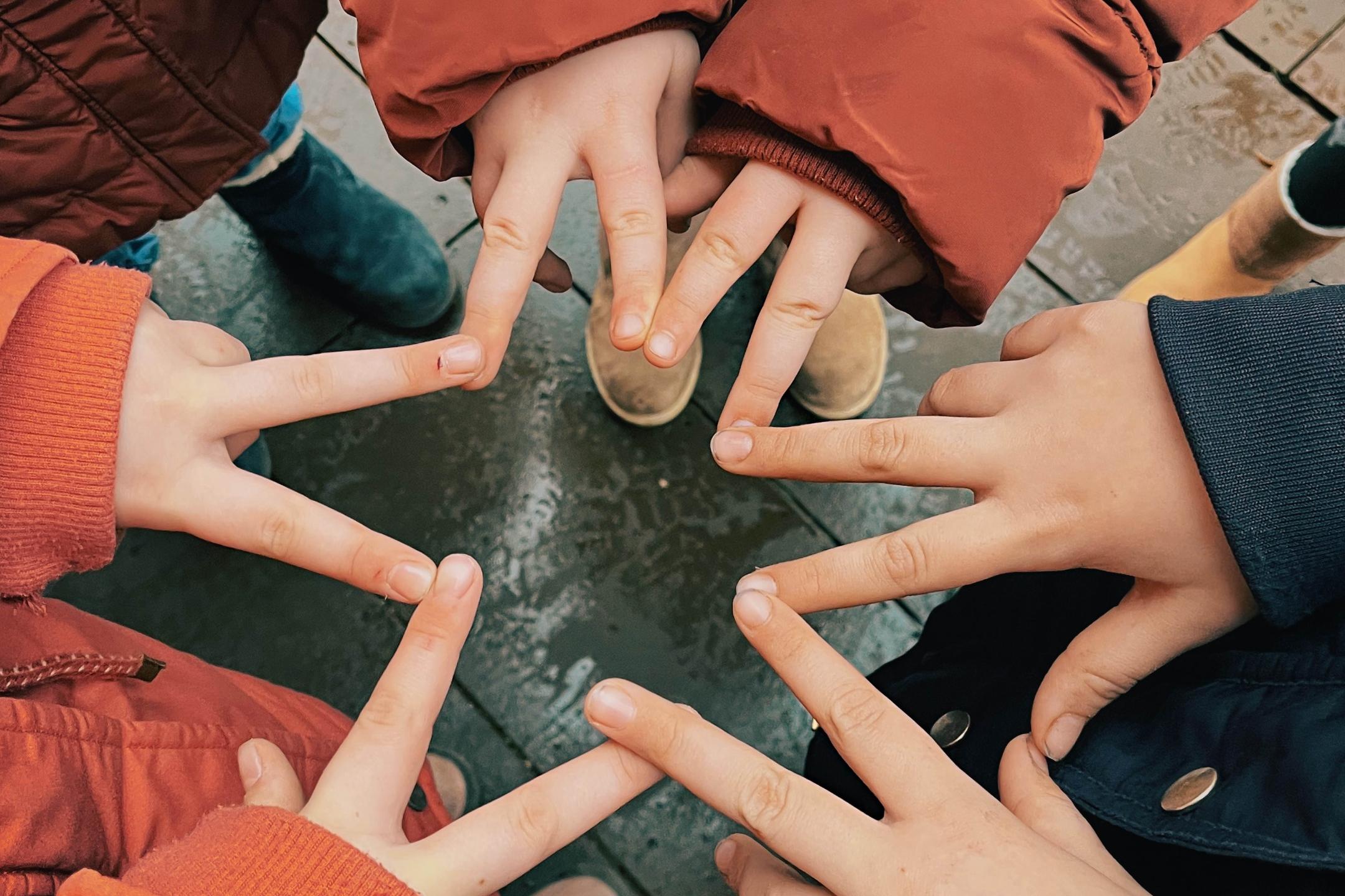 zwei Finger von sechs Händen verbinden sich zu einem Stern