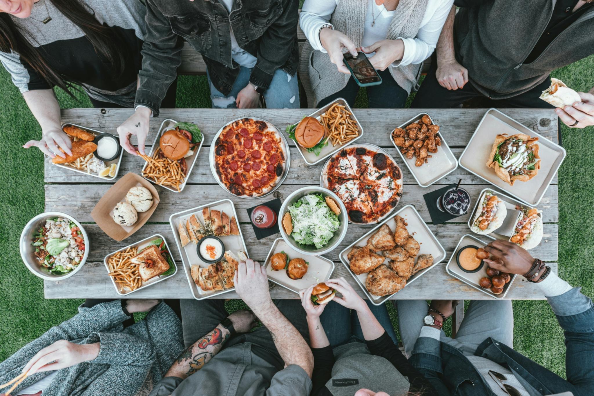 Mehrere Personen sitzen zusammen an einem Tisch und essen, von oben fotografiert