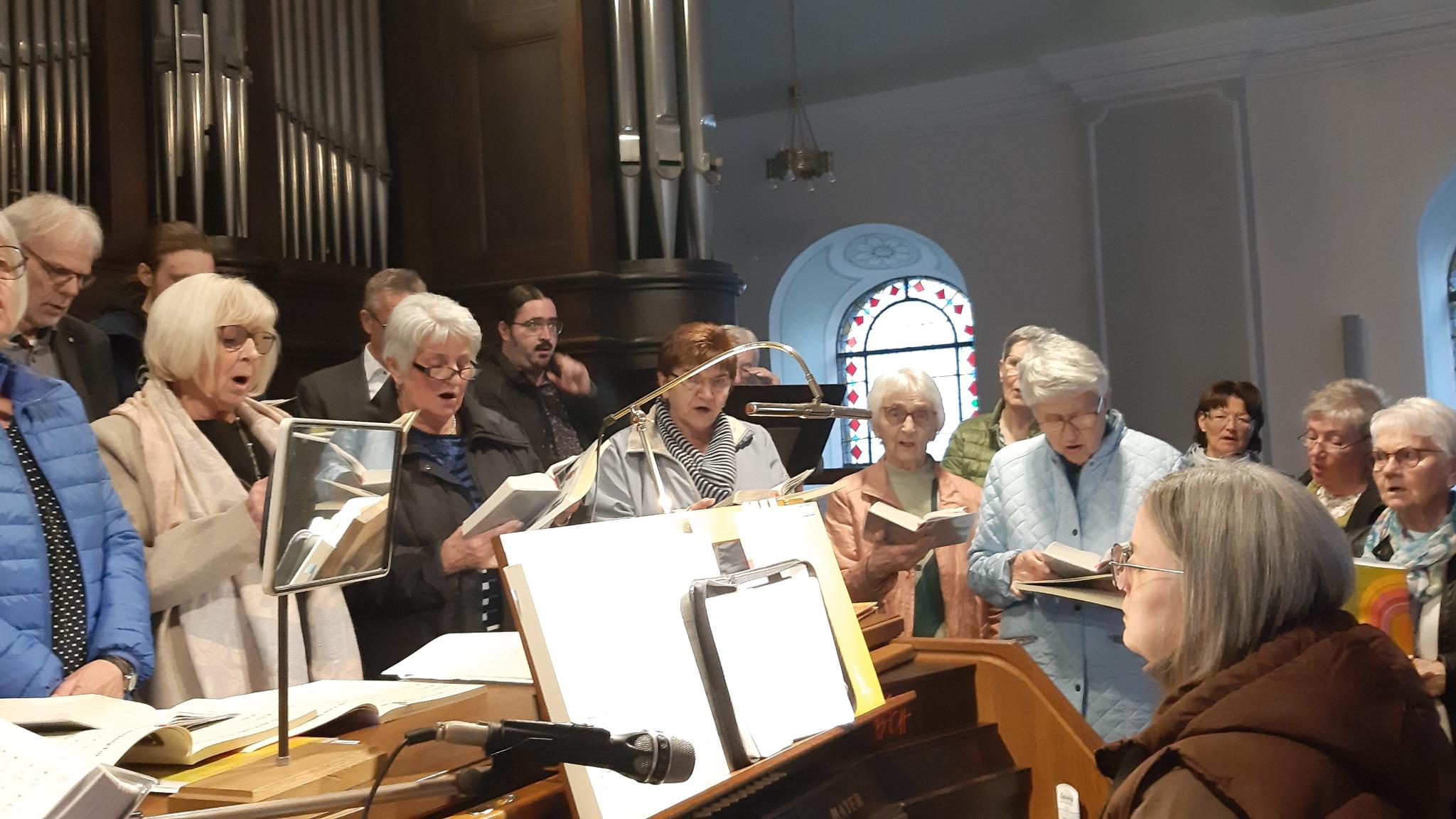 Frauen stehen um eine Organistin auf der Orgelempore und singen