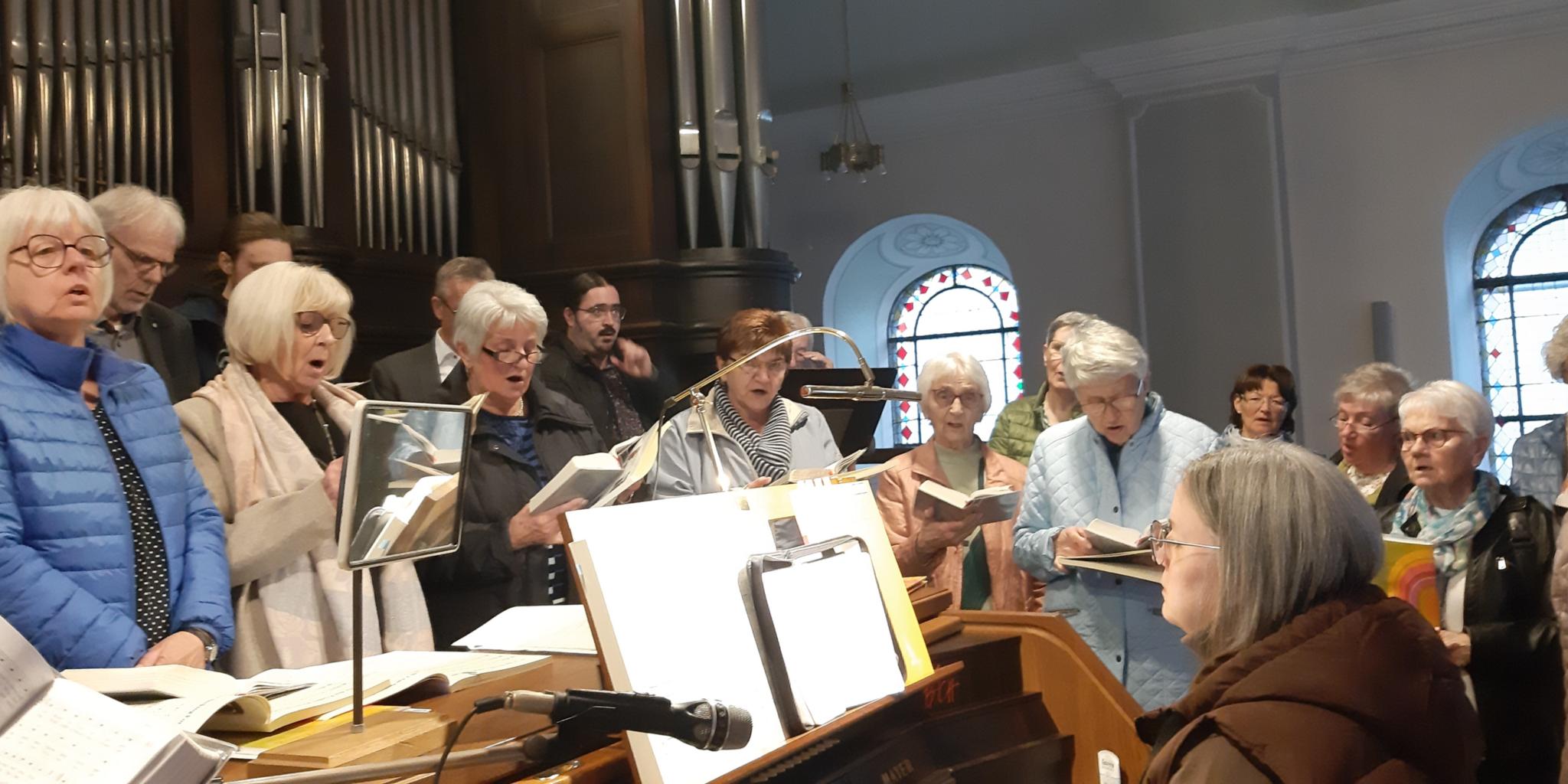 Frauen stehen um eine Organistin auf der Orgelempore und singen